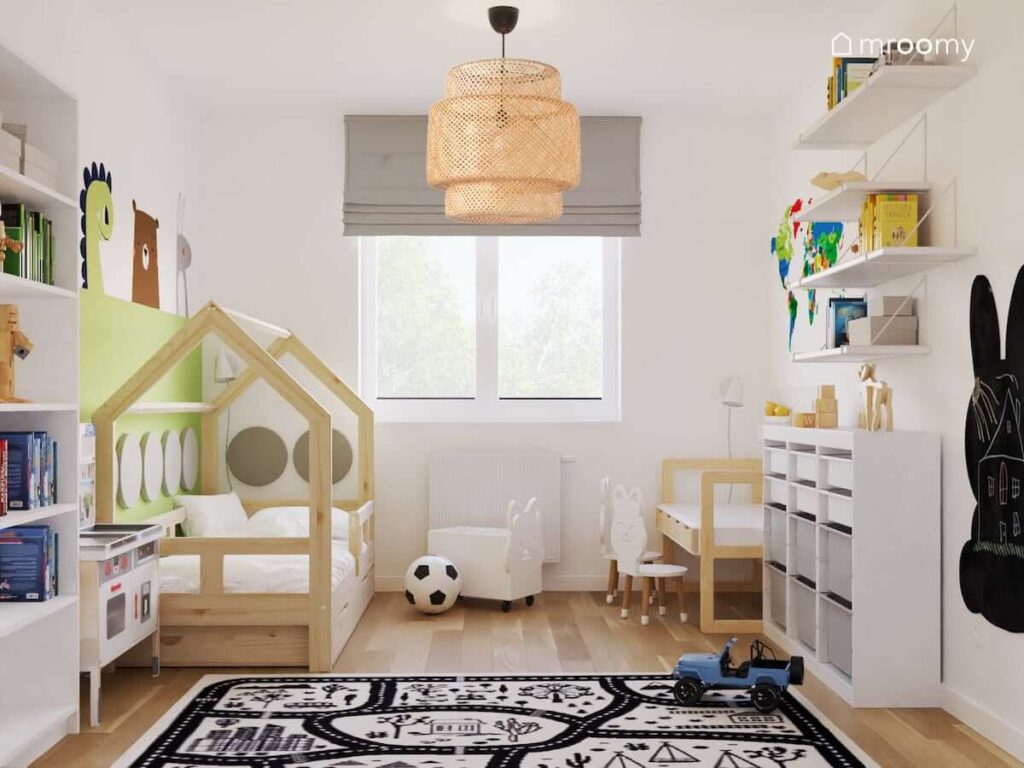 Jasny pokój dla rodzeństwa z drewnianym łóżkiem domkiem oraz białymi meblami i dywanem przedstawiającym miasto