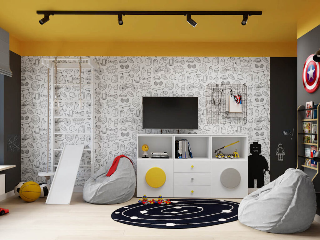 Ściana pokryta młodzieżową tapetą a na niej drabinka gimnastyczna ze zjeżdżalnią telewizor organizer i tablica kredowa w kształcie ludzika Lego w pokoju dla dwóch chłopców