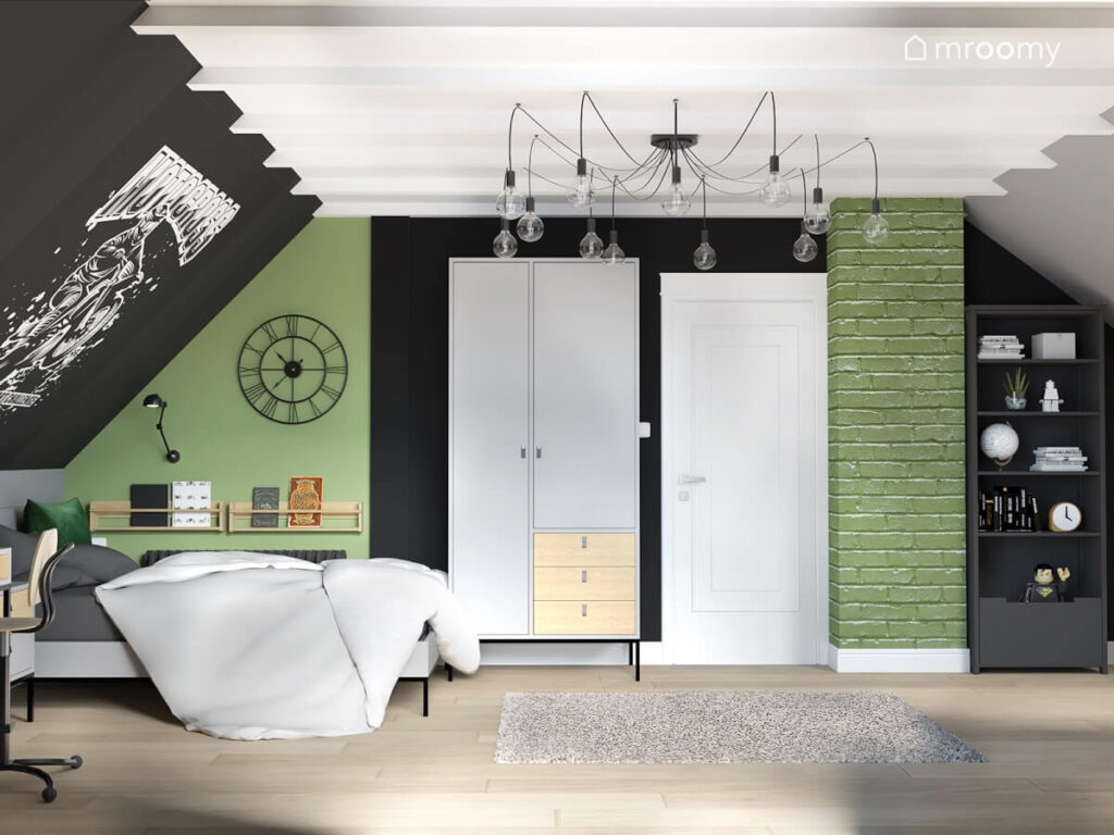 Zielono biało czarny poddaszowy pokój dla chłopca a w nim szara szafa z drewnianymi szufladami rozłożysty żyrandol i metalowy zegar ścienny