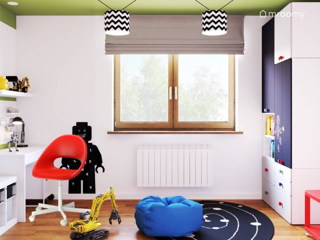 Biały pokój dla chłopca z zielonym sufitem a w nim czarna tablica kredowa w kształcie ludzika Lego czarno biały galaktyczny dywan niebieski worek do siedzenia oraz lampy sufitowe z czarno białymi abażurami