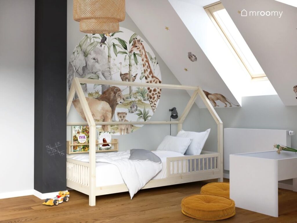Strefa młodszego brata w pokoju dwóch chłopców a w niej drewniane łóżko domek a na ścianach wokół niego naklejki z dzikimi zwierzętami