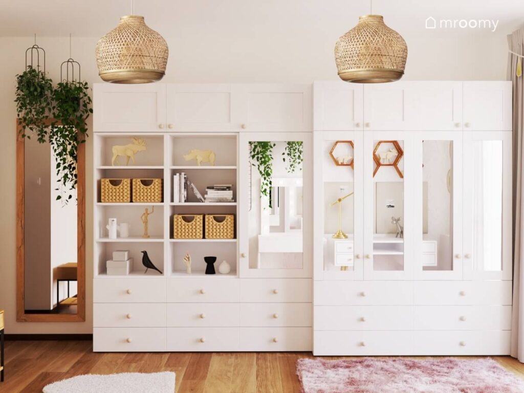 Duże białe szafy modułowe z regałami i lustrzanymi frontami a także lustro w drewnianej ramie kwietniki i bambusowe lampy w pokoju dla nastolatki