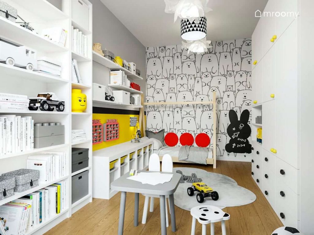 Pokój przedszkolaka z białymi meblami tapetą w czarno białe wzory psy tablicą magnetyczną w kształcie królika i panelami na ścianie obok łóżka