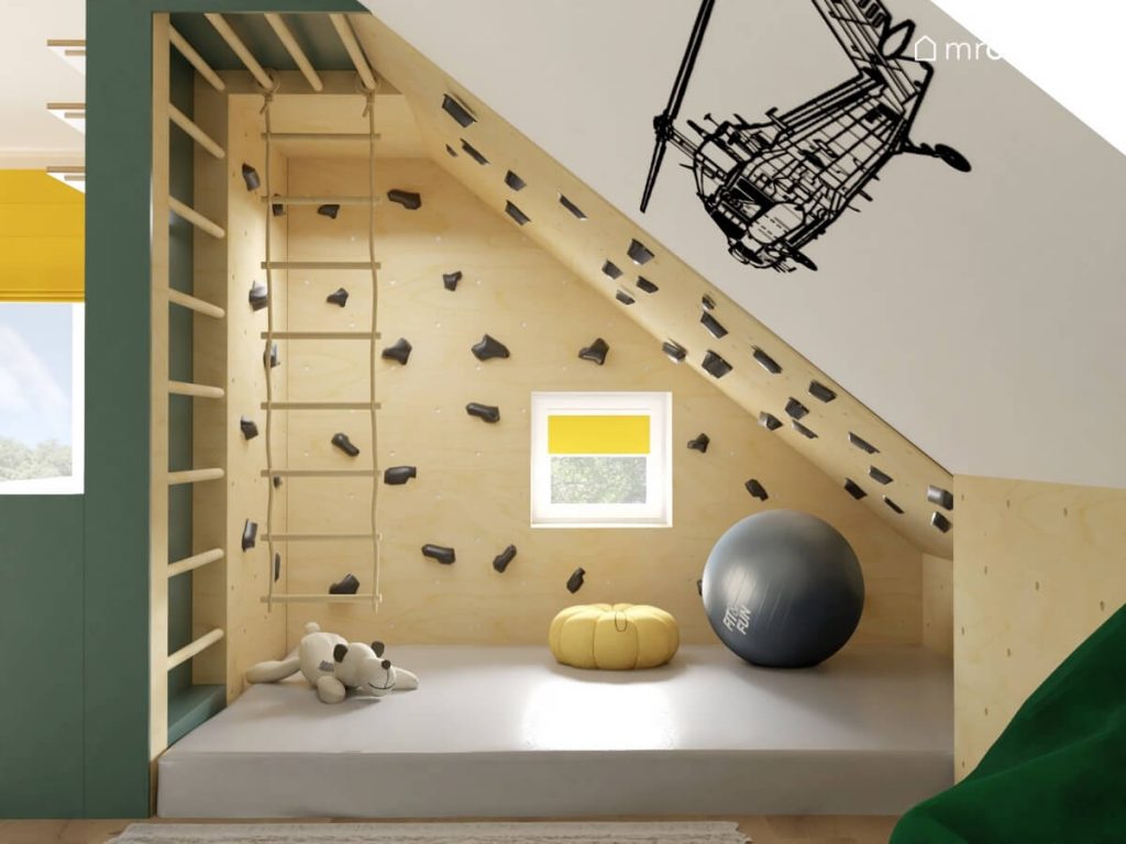 Kącik sportowy w pokoju dla kilkuletniego chłopca a w nim ścianka wspinaczkowa drabinka gimnastyczna i drabinka sznurkowa