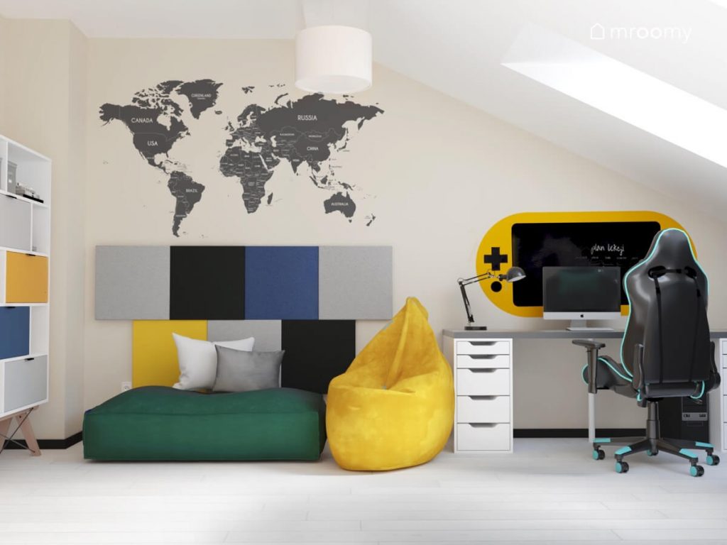 Jasny poddaszowy pokój dla chłopca a w nim wygodne pufy do siedzenia mapa świata na ścianie oraz biurko z fotelem gamingowym oraz gamingową naklejką na ścianie