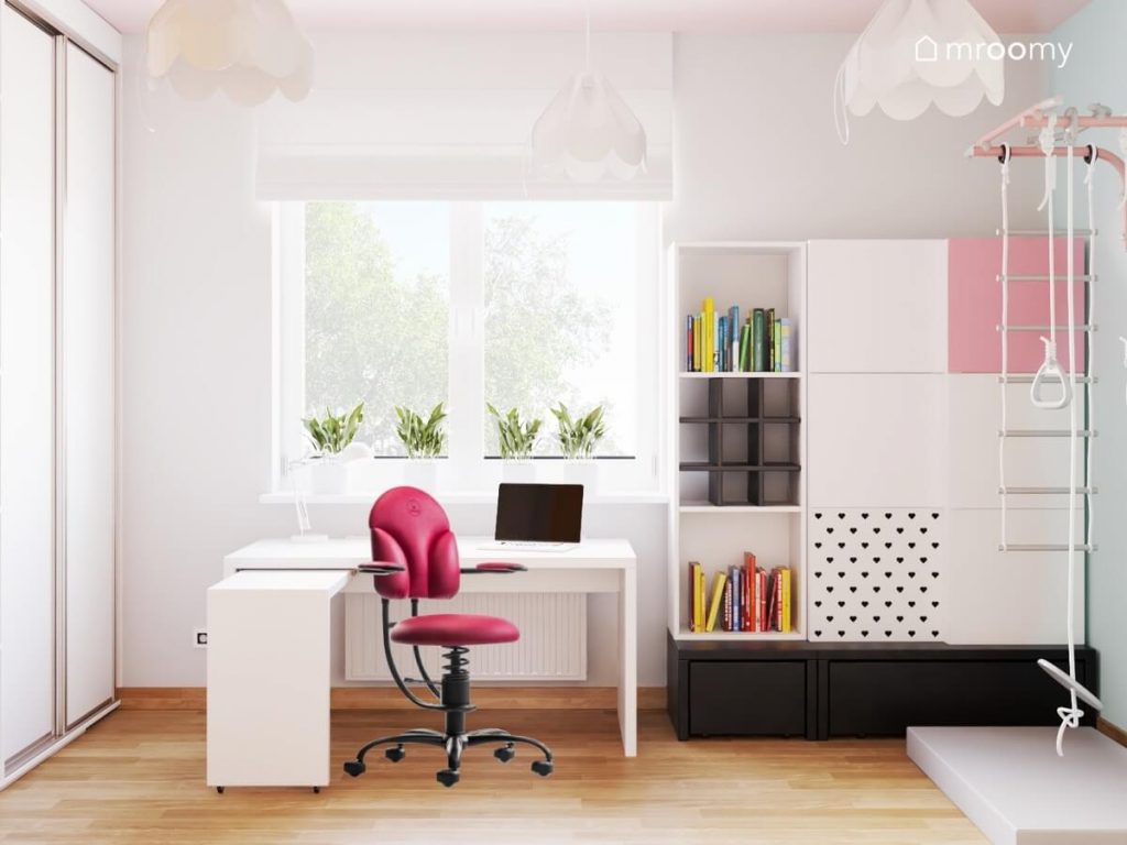 Stefa nauki w pokoju dla nastolatki a w niej białe biurko z różowym fotelem oraz duży kwadratowy regał z podestem i metalowymi nakładkami na fronty