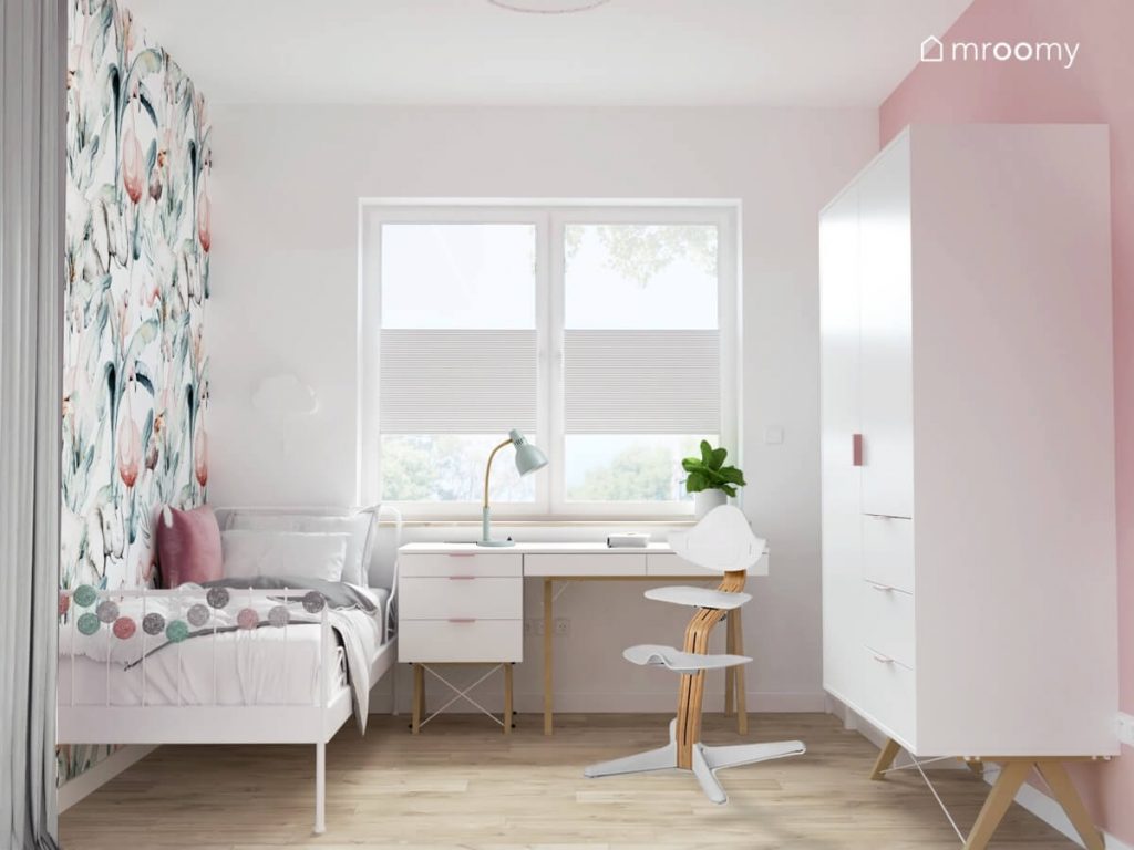 Mały jasny pokój dla dziewczynki a w nim białe łóżko ozdobione girlandą cotton balls białe biurko z kontnerkiem na drewnianych nogach oraz duża biała szafa