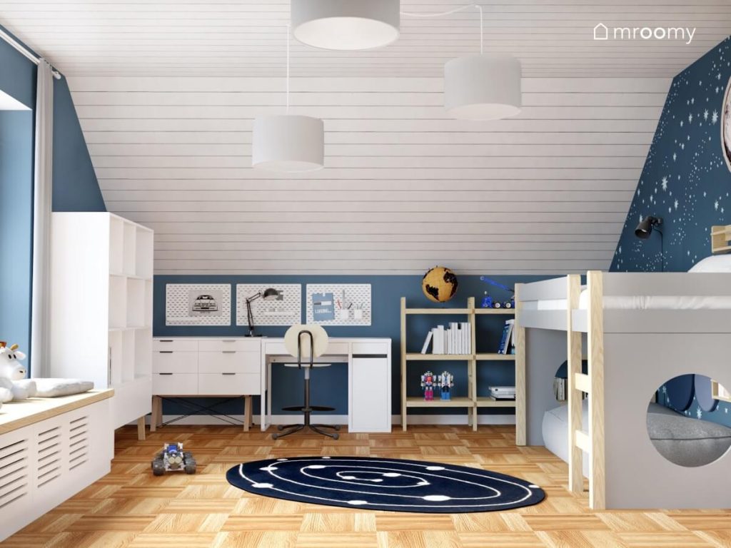 Biało niebieski poddaszowy pokój dla chłopca a w nim białe i drewniane meble łóżko na antresoli oraz kosmiczne motywy
