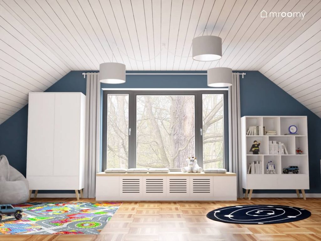 Biało niebieski poddaszowy pokój dla chłopca z sufitem pokrytym tapetą w linie oraz z białymi meblami kosmicznym dywanem i dywanem z motywem miasta