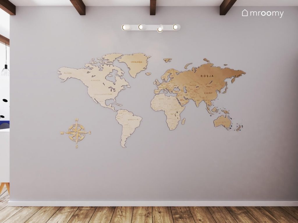 Wielkoformatowa drewniana mapa świata na szarej ścianie w pokoju nastolatka