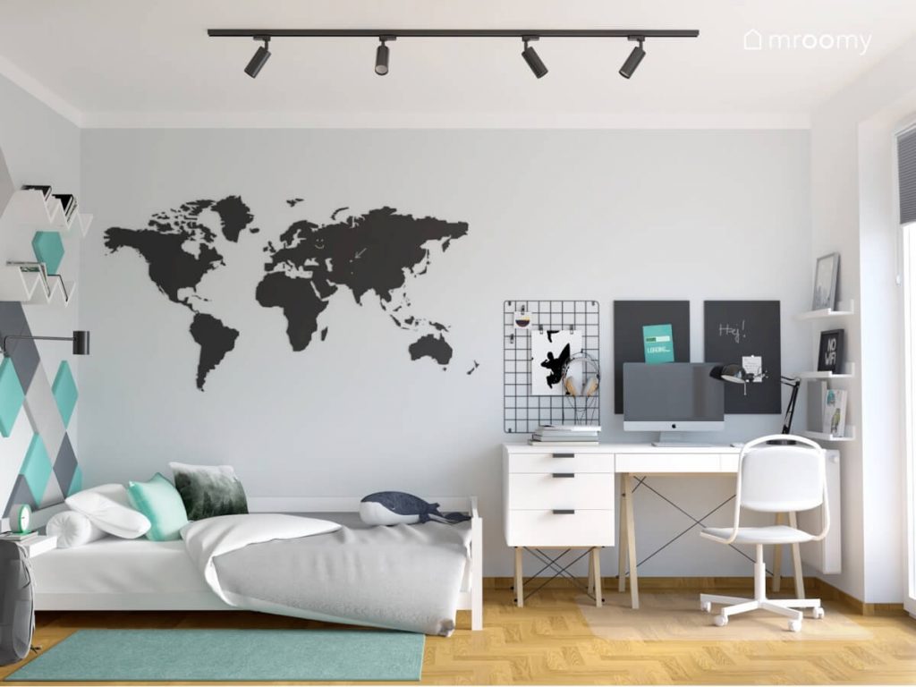 Biało szary pokój dla chłopca w wieku szkolnym a w nim niskie białe łóżko białe biurko z organizerami i tablicami kredowymi a na ścianie mapa świata
