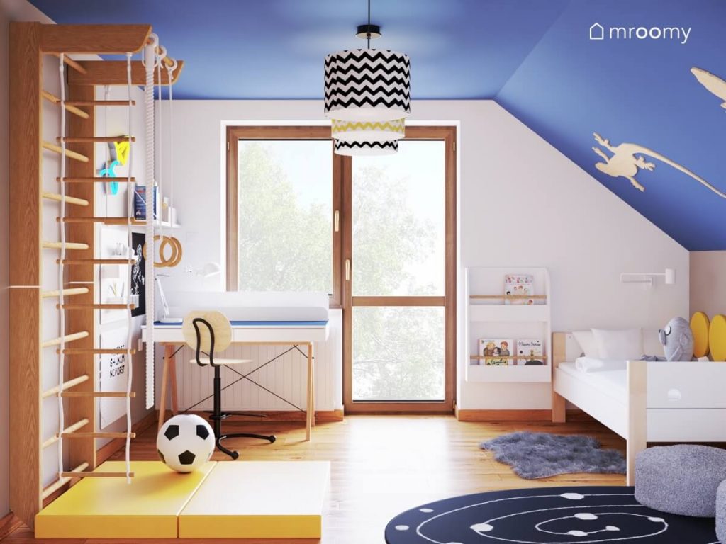 Szaro niebieski poddaszowy pokój dla chłopca z biało drewnianymi meblami galaktycznym dywanem oraz lampami w abażurach we wzorki
