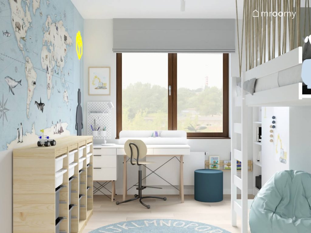 Jasny pokój dla chłopca a w nim białe i drewniane meble błękitny dywan z alfabetem oraz tapeta z mapą świata