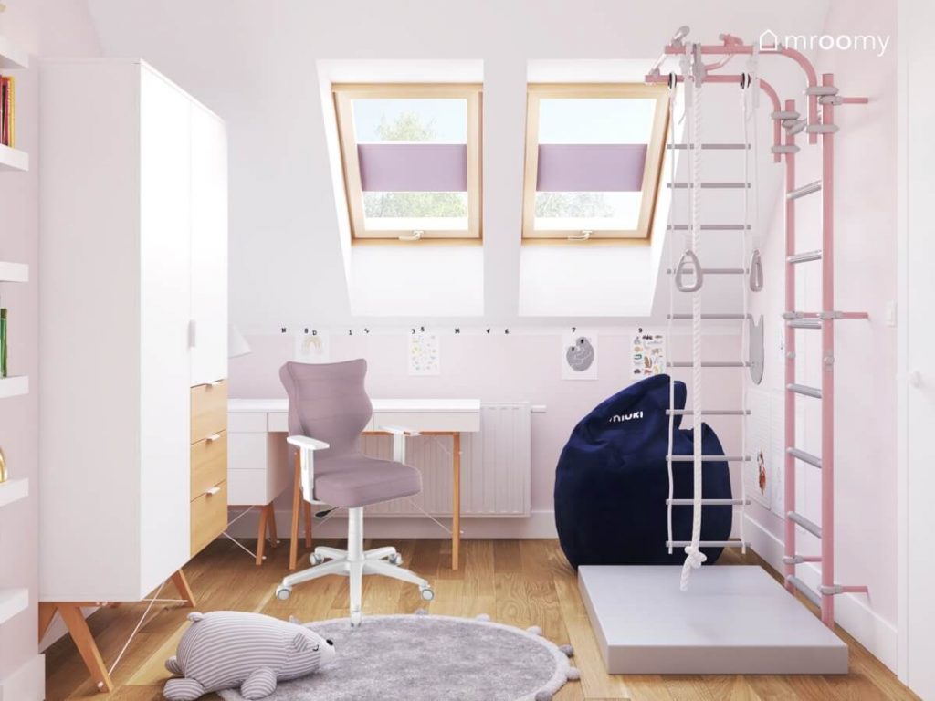 Biały poddaszowy pokój pięciolatki z białymi meblami z drewnianymi elementami drabinką gimnastyczną z materacem granatową pufą oraz szarym dywanem