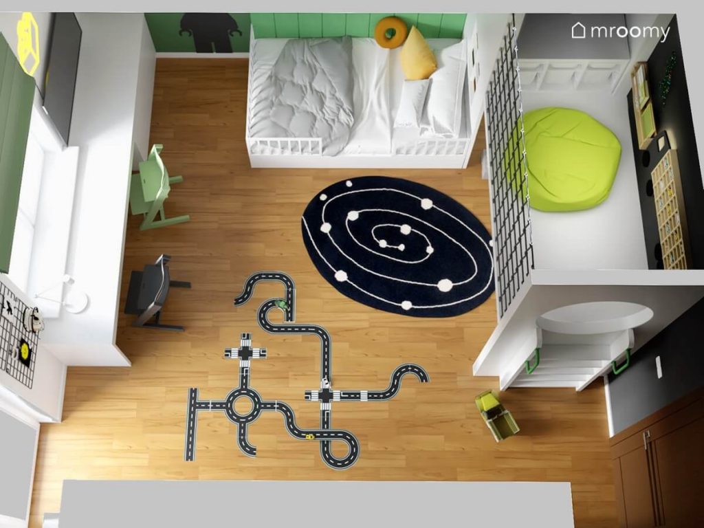 Widok z góry na pokój dla chłopca w którym znajduje się białe łóżko antresola z pufą i półkami białe biurko duża szafa galaktyczny dywan i naklejka podłogowa w kształcie jezdni
