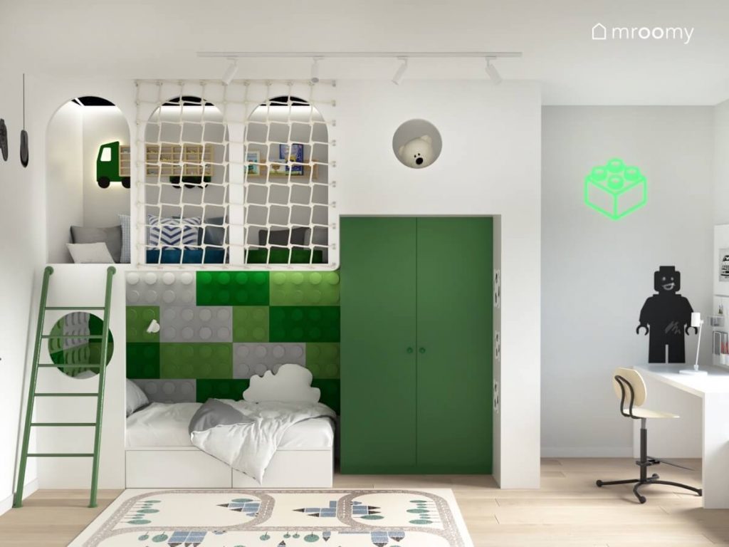 Biała antresola w pokoju dla chłopca a na niej miejsce do zabawy a pod spodem łóżko uzupełnione zielonymi panelami ściennymi w kształcie klocków oraz zielona szafa