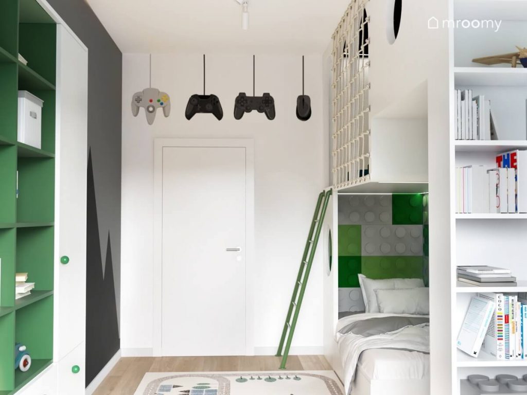 Jasny pokój dla chłopca a w nim biała antresola łóżko uzupełnione panelami ściennymi w kształcie klocków a nad drzwiami naklejki z padami