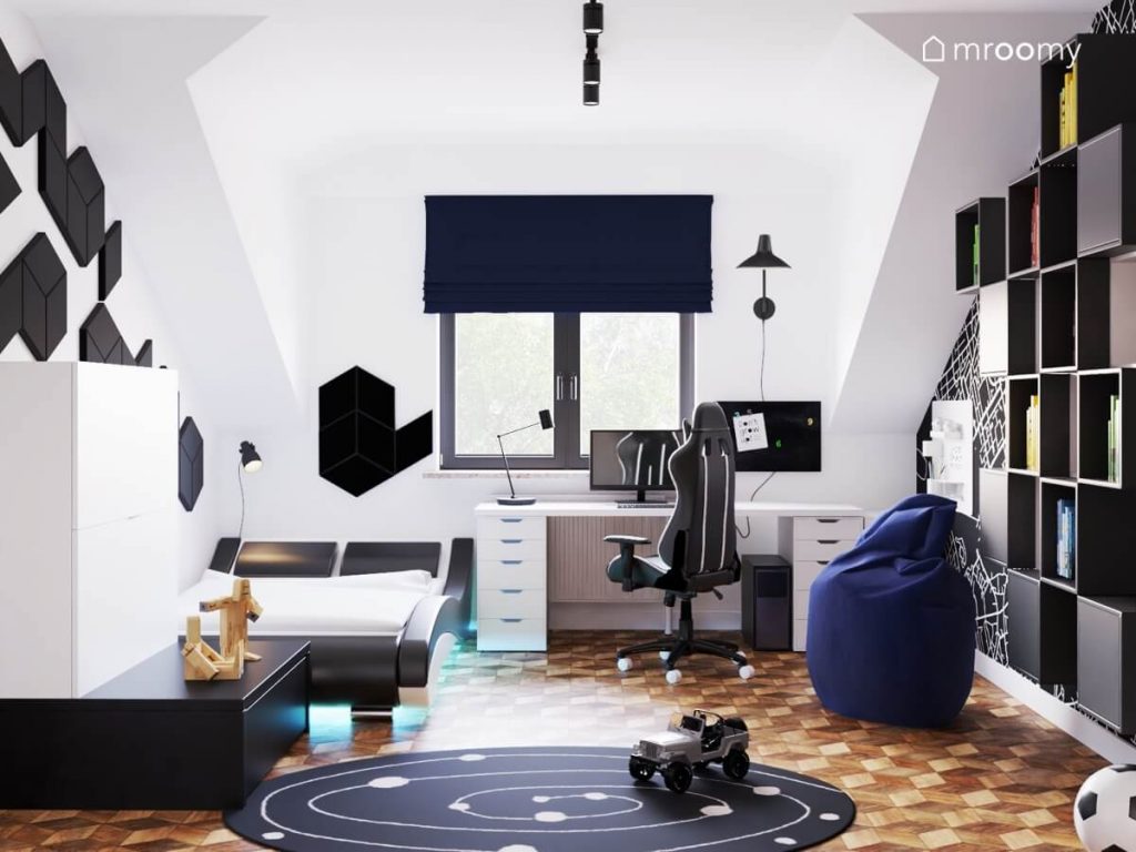 Jasny młodzieżowy pokój dla nastolatka a w nim białe meble i czarne meble granatowa pufa i roleta oraz galaktyczny dywan