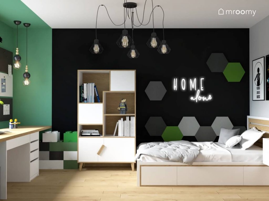 Czarno zielono szaro biały pokój nastoletniego chłopca a w nim ozdobne lampy biało drewniane łóżko i duży regał a także ledon na ścianie i sześciokątne panele ścienne