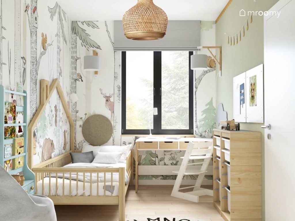 Biało zielony pokój małego chłopca a w nim drewniano białe meble leśna tapeta oraz lampa z kloszem z naturalnych materiałów