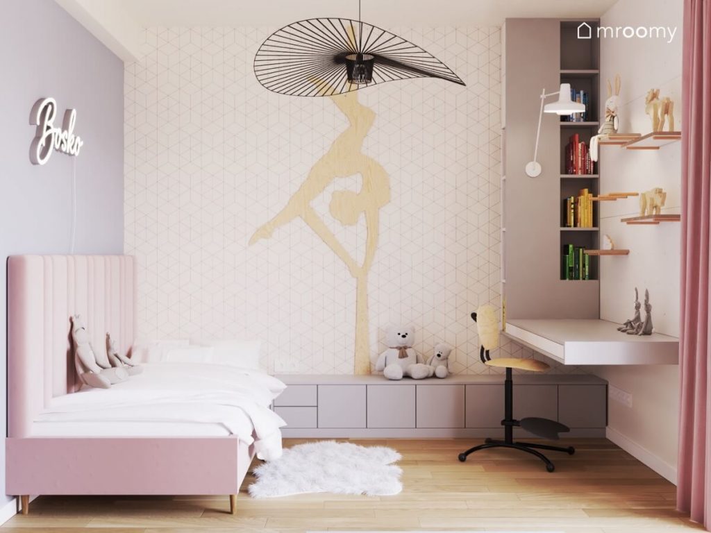 Jasny pokój dla dziewczynki w wieku szkolnym a w nim różowe łóżko z bocznym zagłówkiem szare meble geometryczna tapeta akrobatka ze sklejki i duża czarna lampa sufitowa
