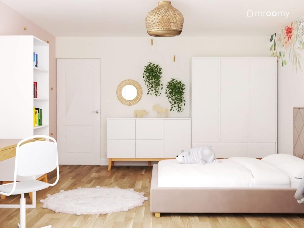 Jasny pokój dziewczynki w wieku szkolnym a tak białe meble z drewnianymi elementami kwietniki tapicerowane łóżko oraz okrągłe lustro i lampa bambusowa