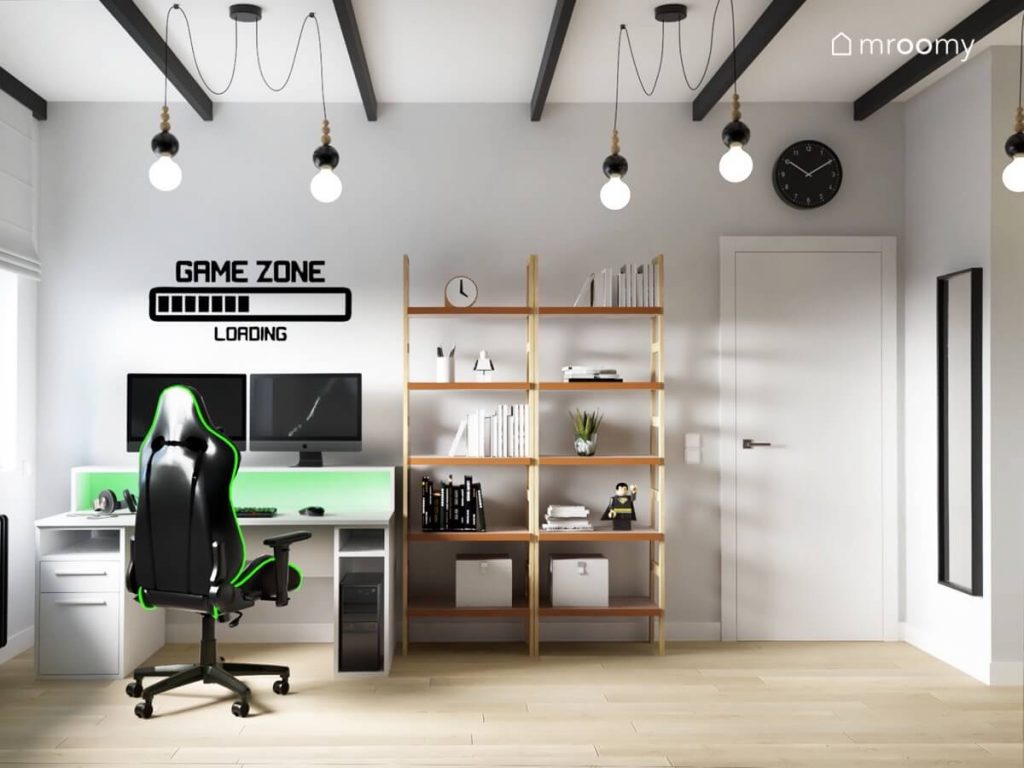 Strefa nauki i rozrywki w pokoju dla chłopca z w niej biało zielone biurko czarno zielony fotel gamingowa naklejka a obok dwa drewniane regały