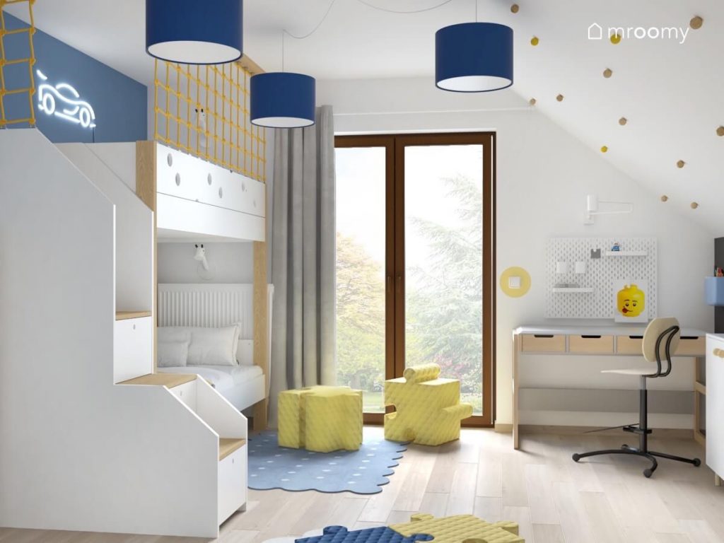 Biało niebieski poddaszowy pokój chłopca a w nim antresola biało drewniane biurko pufki w kształcie klocków oraz niebieskie lampy sufitowe