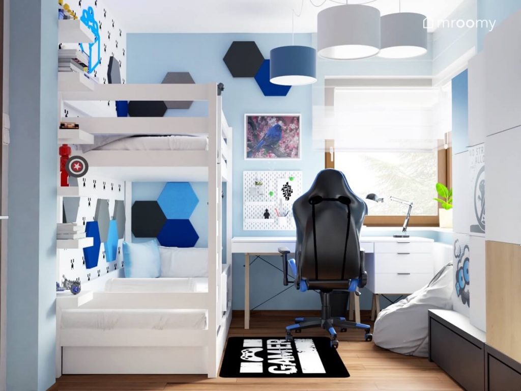 Biało niebieski pokój dla chłopca z białym łóżkiem piętrowym białym biurkiem na drewnianych nogach z kontenerkiem fotelem gamingowym oraz ścianami uzupełnionymi sześciokątnymi panelami