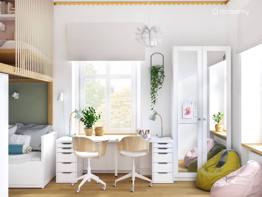 Białe biurko z dwoma kontenerkami i biało drewnianymi krzesłami a obok szafa z lustrzanymi frontami na ścianie kwietnik a u sufitu ozdobna lampa w pokoju dwóch dziewczynek