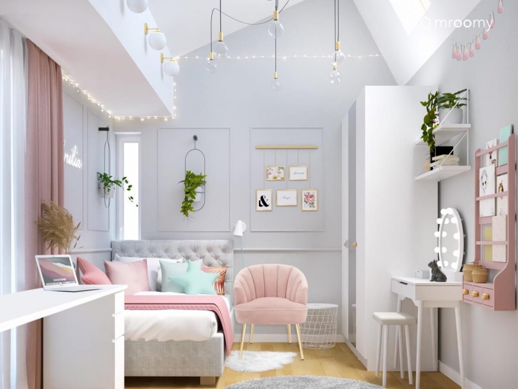 Biało szary pokój dla nastolatki a w nim szare łóżko z pikowanym zagłówkiem różowy fotel biała szafa toaletka a na ścianie kwietniki i ozdobna sztukateria