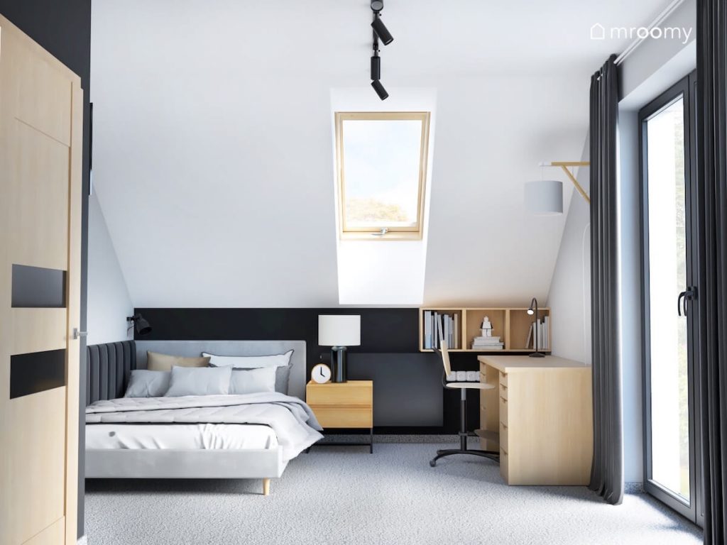 Monochromatyczny poddaszowy pokój dla chłopca w wieku szkolnym a w nim szare łóżko oraz drewniane półki biurko i szafka nocna