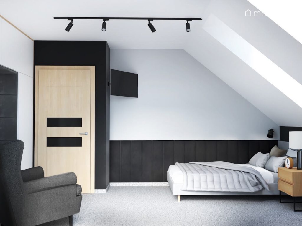 Poddaszowy pokój dla chłopca z biało szaro czarnymi ścianami szarym łóżkiem i fotelem oraz pionowymi miękkimi panelami ściennymi