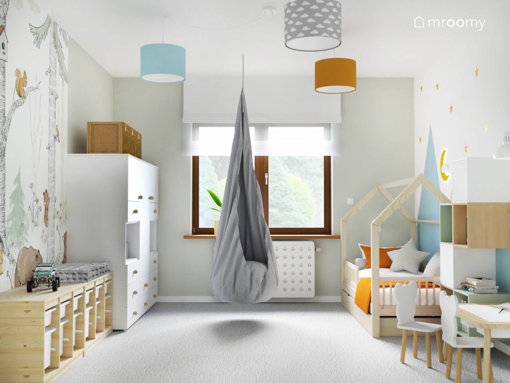 Jasny pokój dla trzylatka a w nim szary fotel kokon kolorowe lampy sufitowe oraz białe i drewniane meble