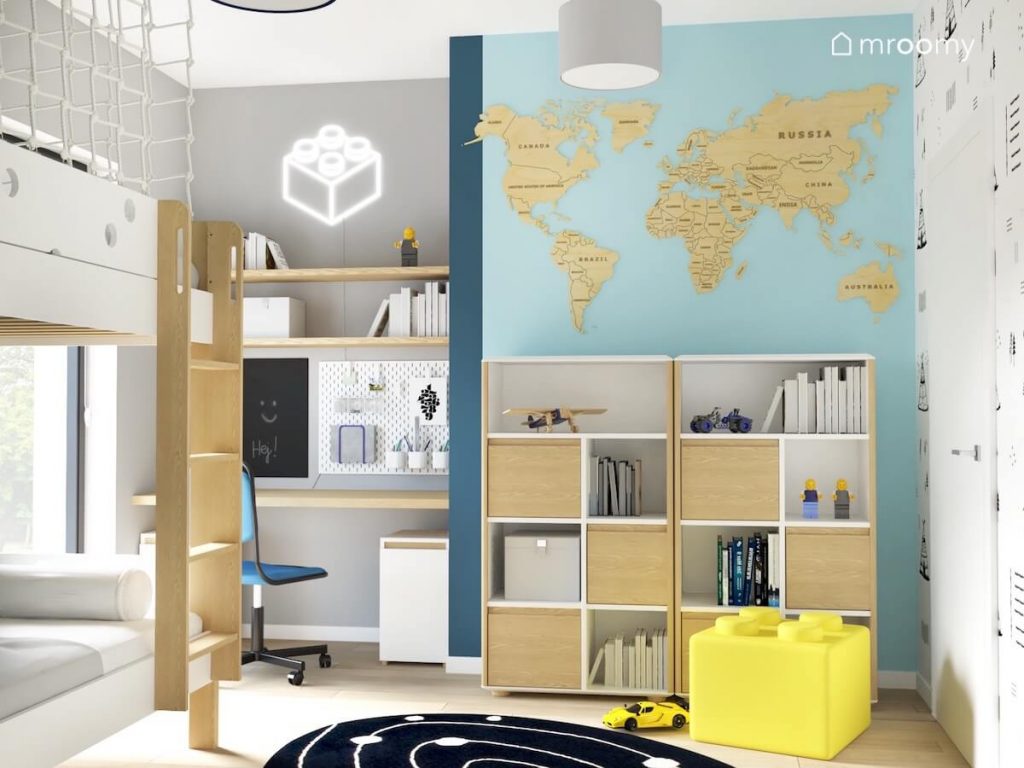 Biało szaro niebieski pokój dla chłopca a w nim biało drewniane meble ledon i pufka w kształcie klocka oraz drewniana mapa świata