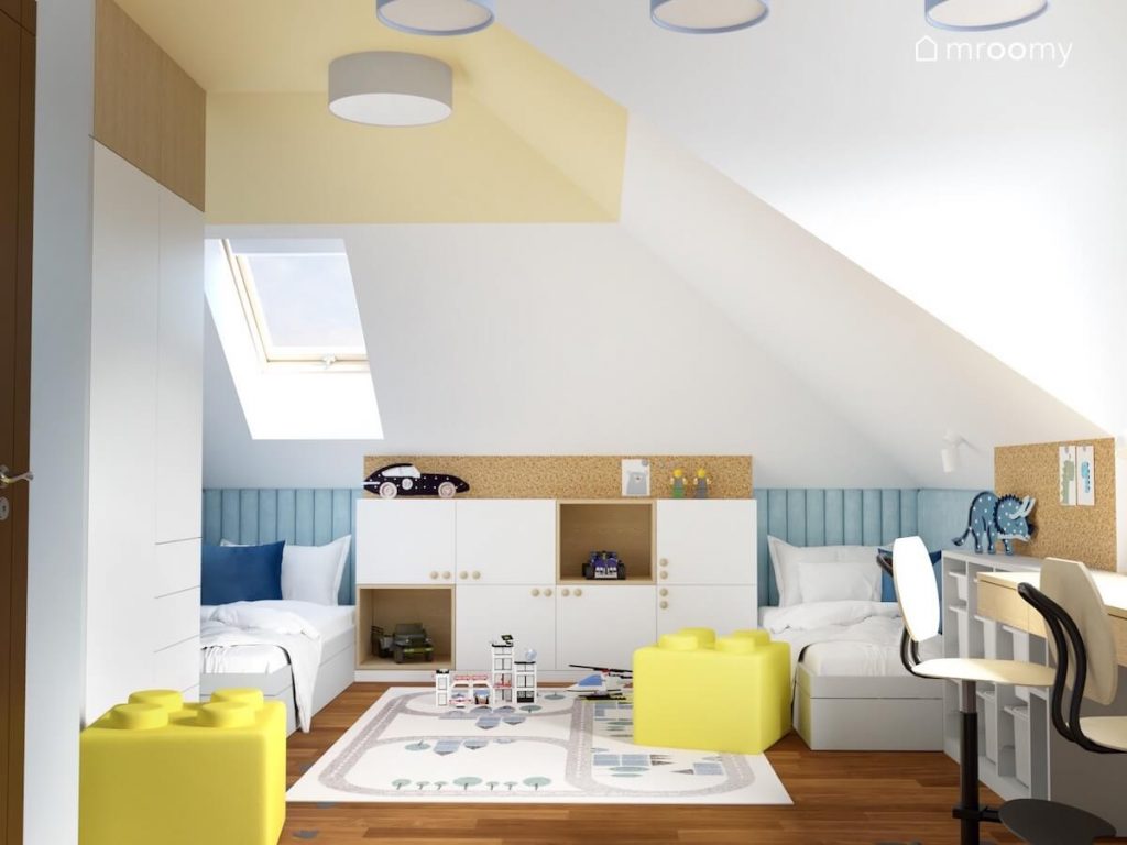 Jasny poddaszowy pokój dwóch chłopców a w nim biało drewniane meble jasnoniebieskie panele ścienne pod skosem oraz żółte pufki klocki i dywan z miastem
