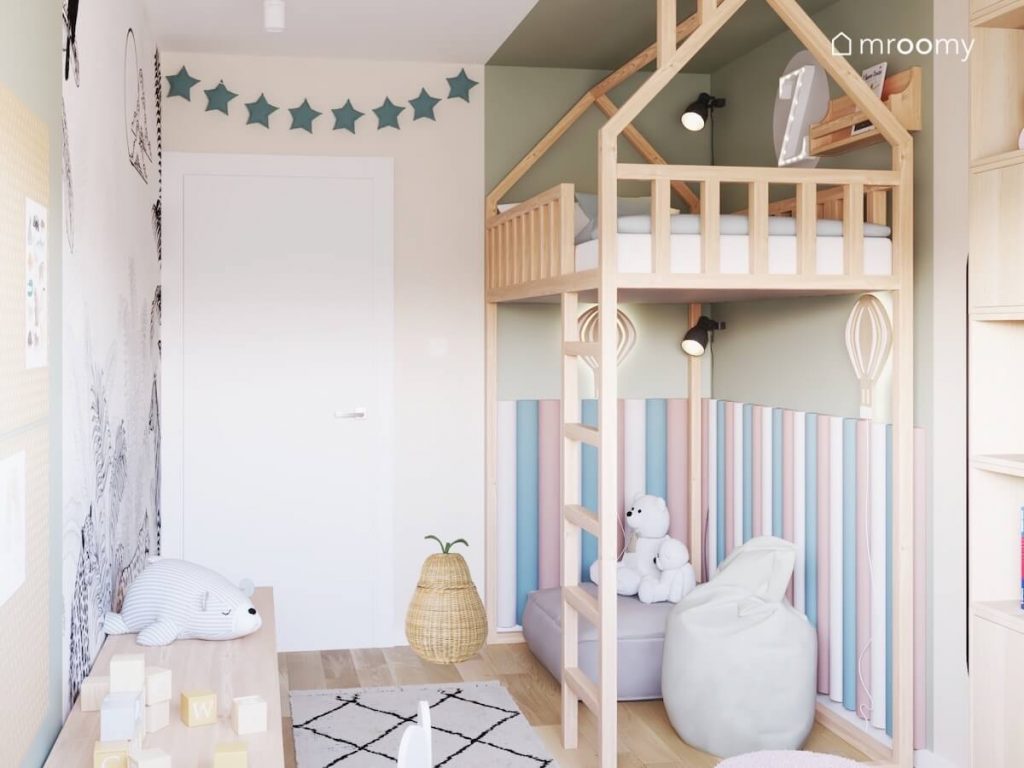 Drewniana antresola w kształcie domku w pokoju dziewczynki a pod nią kącik otoczony kolorowymi panelami a w nim wygodne pufy