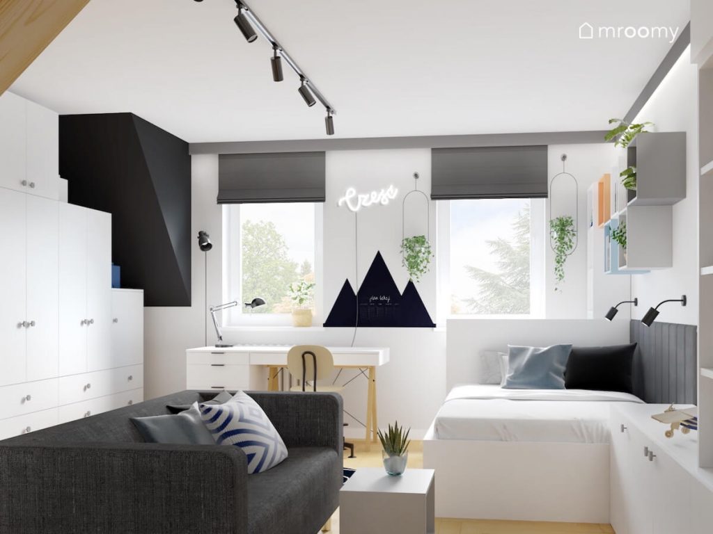 Jasny młodzieżowy pokój dla chłopca a w nim białe meble szara sofa oraz tablica kredowa w kształcie gór