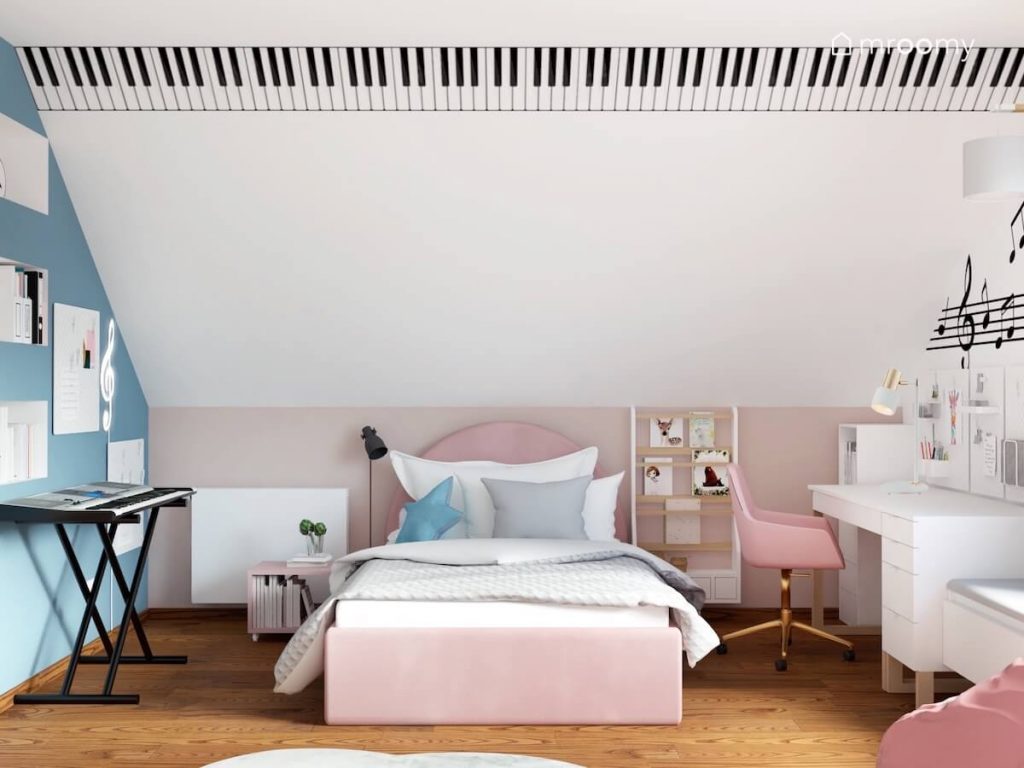 Biały skos z naklejką imitującą klawisze pianina a pod spodem tapicerowane różowe łóżko keyboard oraz biblioteczka w pokoju dziewczynki