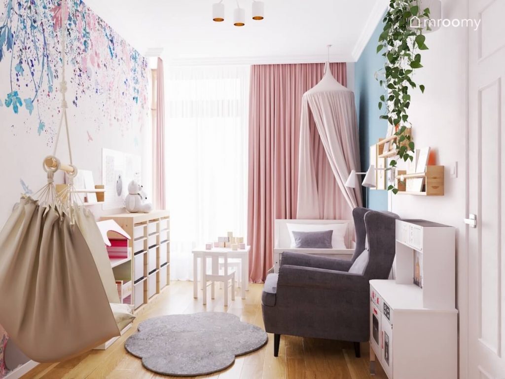 Biało niebieski pokój małej dziewczynki z szarym fotelem dywanem chmurką tapetą w kwiaty fotelem wiszącym i łóżkiem z baldachimem