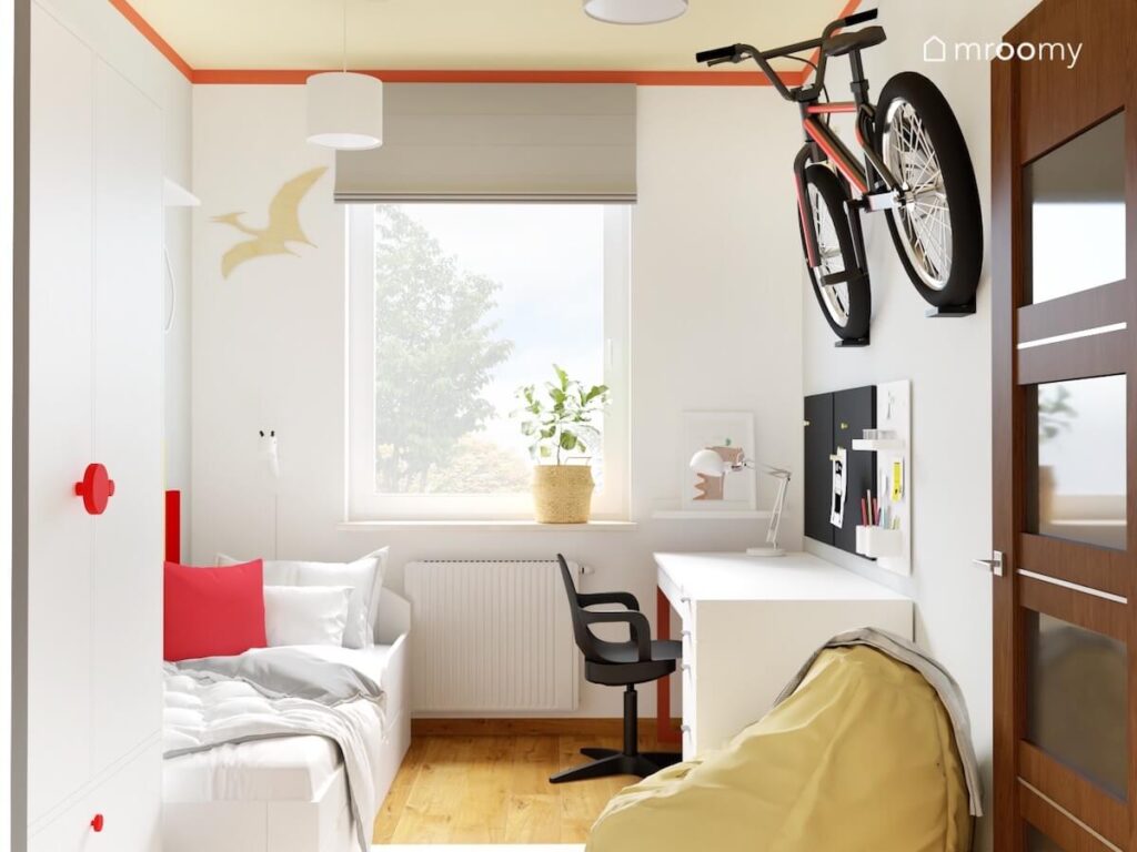 Beżowy pokój dla chłopca a w nim białe meble jasnożółta pufa uchwyt na rower na ścianie oraz sklejkowe dinozaury