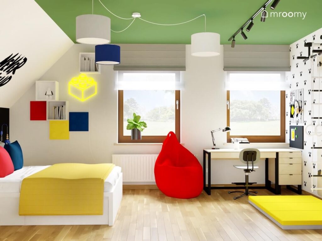 Biało szaro zielony pokój dla siedmiolatka a w nim jasne meble żółte dodatki oraz czerwona pufa a na suficie lampa z abażurami w różnych kolorach