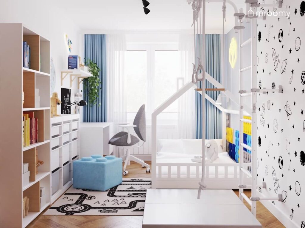 Jasny pokój dla czteroletniego chłopca a w nim białe meble łóżko domek ścianka wspinaczkowa a na podłodze dywan z drogą