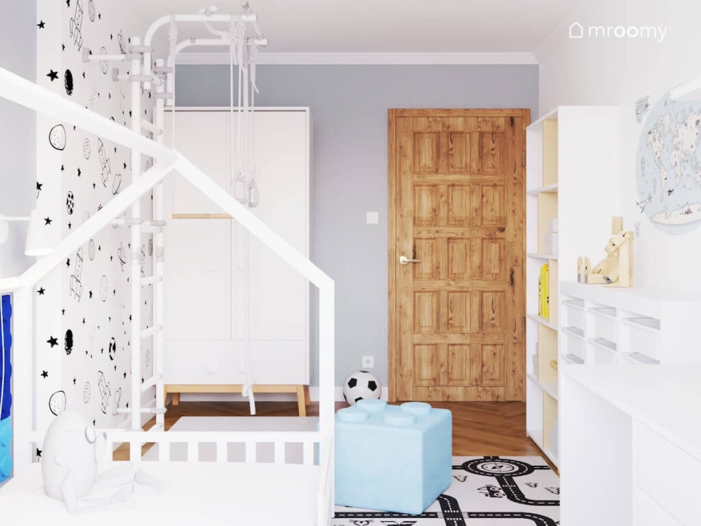 Biało szaroniebieski pokój dla czterolatka a w nim biała szafa na drewnianych nogach drabinka gimnastyczna i pufa w kształcie klocka