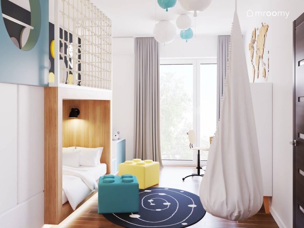 Biały pokój dla pięciolatka a w nim drewniana antresola fotel kokon pufki klocki i galaktyczny dywan