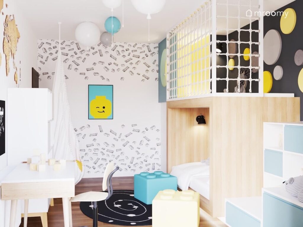 Jasny pokój dla kilkuletniego chłopca a w nim drewniana antresola fotel kokon lampy balony i tapeta w klocki na ścianie