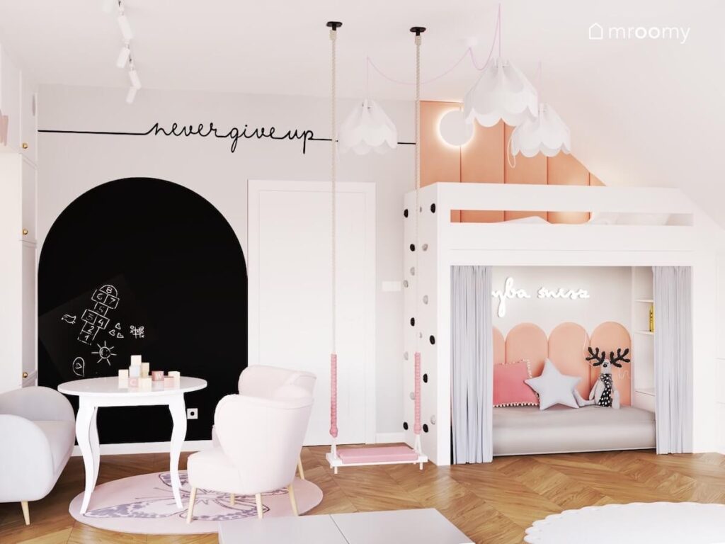 Jasny pokój dla dziewczynki z białymi meblami czarną powierzchnią kredową przytulnym kącikiem pod antresolą huśtawką i lampami bezami