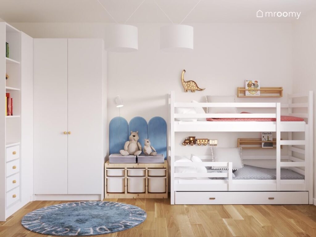 Dwudrzwiowa biała szafa drewniany regał z pojemnikami oraz białe łóżko piętrowe a na podłodze dywan z alfabetem w pokoju dla rodzeństwa