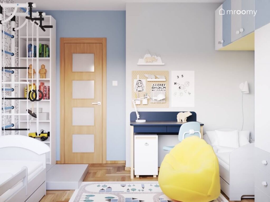 Niebiesko szary pokój dla rodzeństwa a w nim drabinka gimnastyczna granatowe biurko oraz żółta pufa