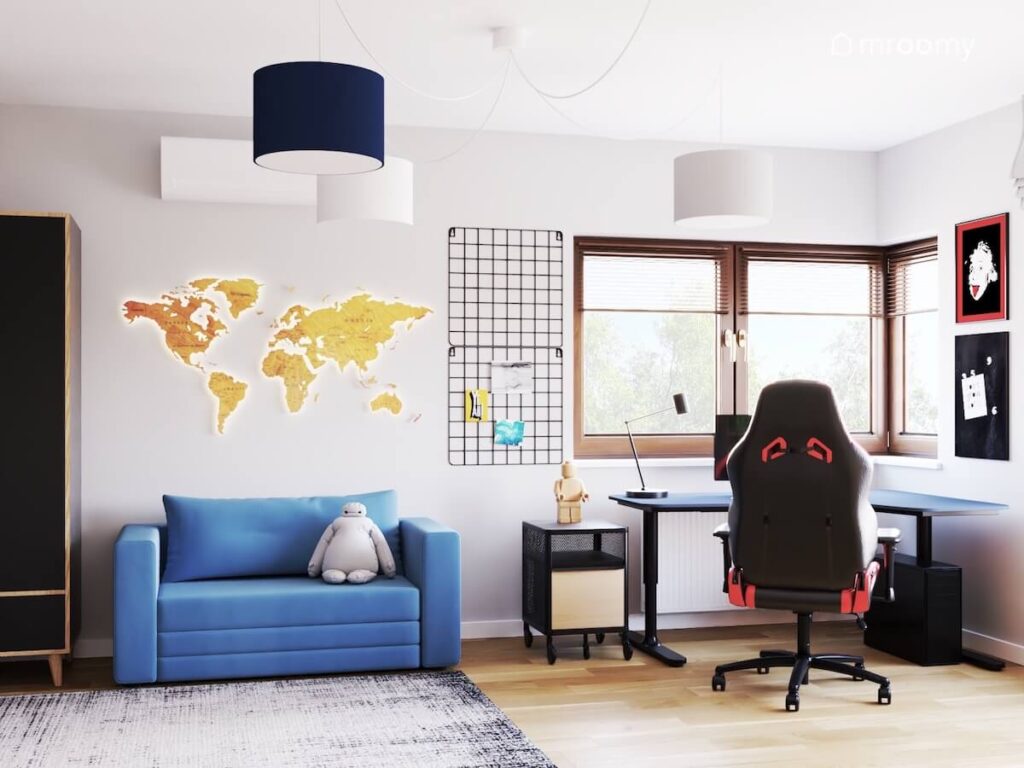 Strefa nauki w pokoju czternastolatka a w niej granatowe biurko i fotel gamingowy a obok organizery niebieska kanapa i drewniana mapa świata